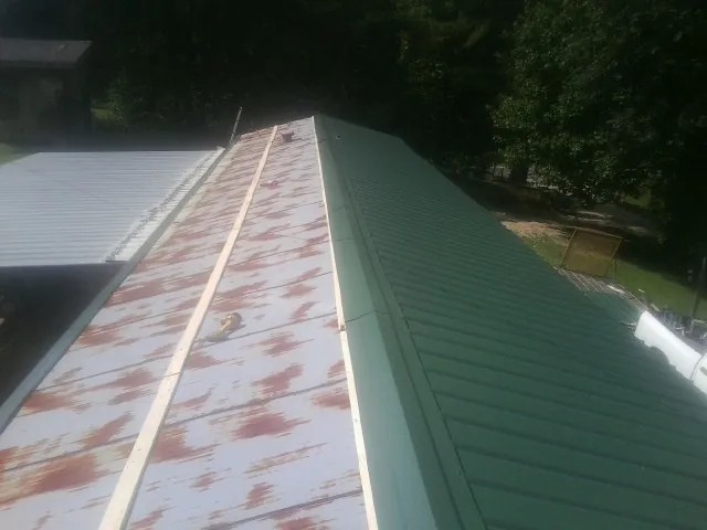 Old rusted panels beside newly installed green metal roofing — Wind Damage Roof Repair by Roofing Brothers in Stanwood