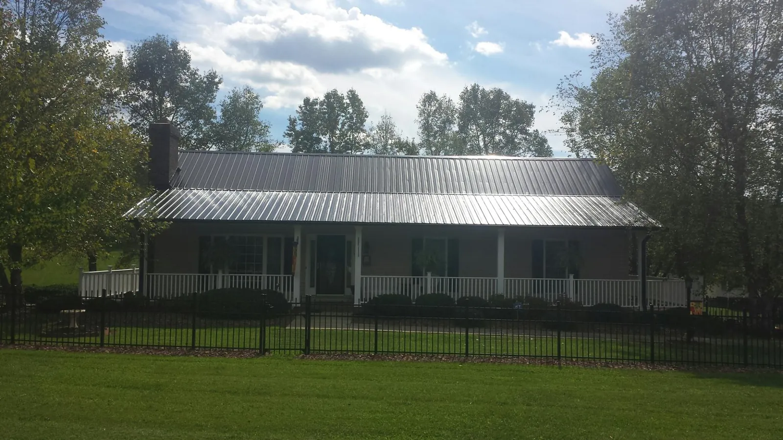 Gray metal roof on a brick ranch with a full width front porch — Gutter Guard Installation work by our crew in Stanwood